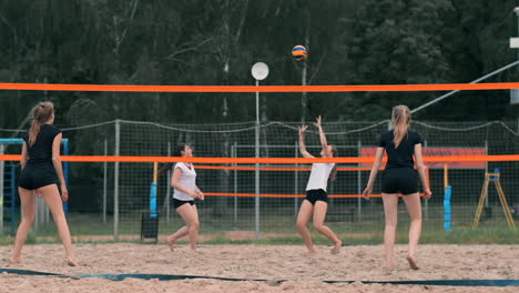 Junge-Frau-Spielt-In-Einer-Mannschaft-Volleyball-Am-Strand-Und-Führt-Einen-Angriff-Durch,-Indem-Sie-Den-Ball-Schlägt.-Mädchen-Schlägt-In-Zeitlupe-Den-Ball-Und-Führt-Einen-Angriff-Durch-Das-Netz-Aus.